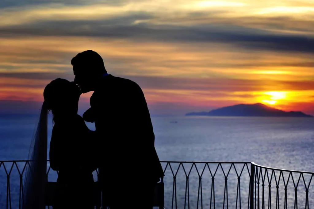 Bride and groom at sunset on the Amalfi Coast with the island of Capri on the horizon